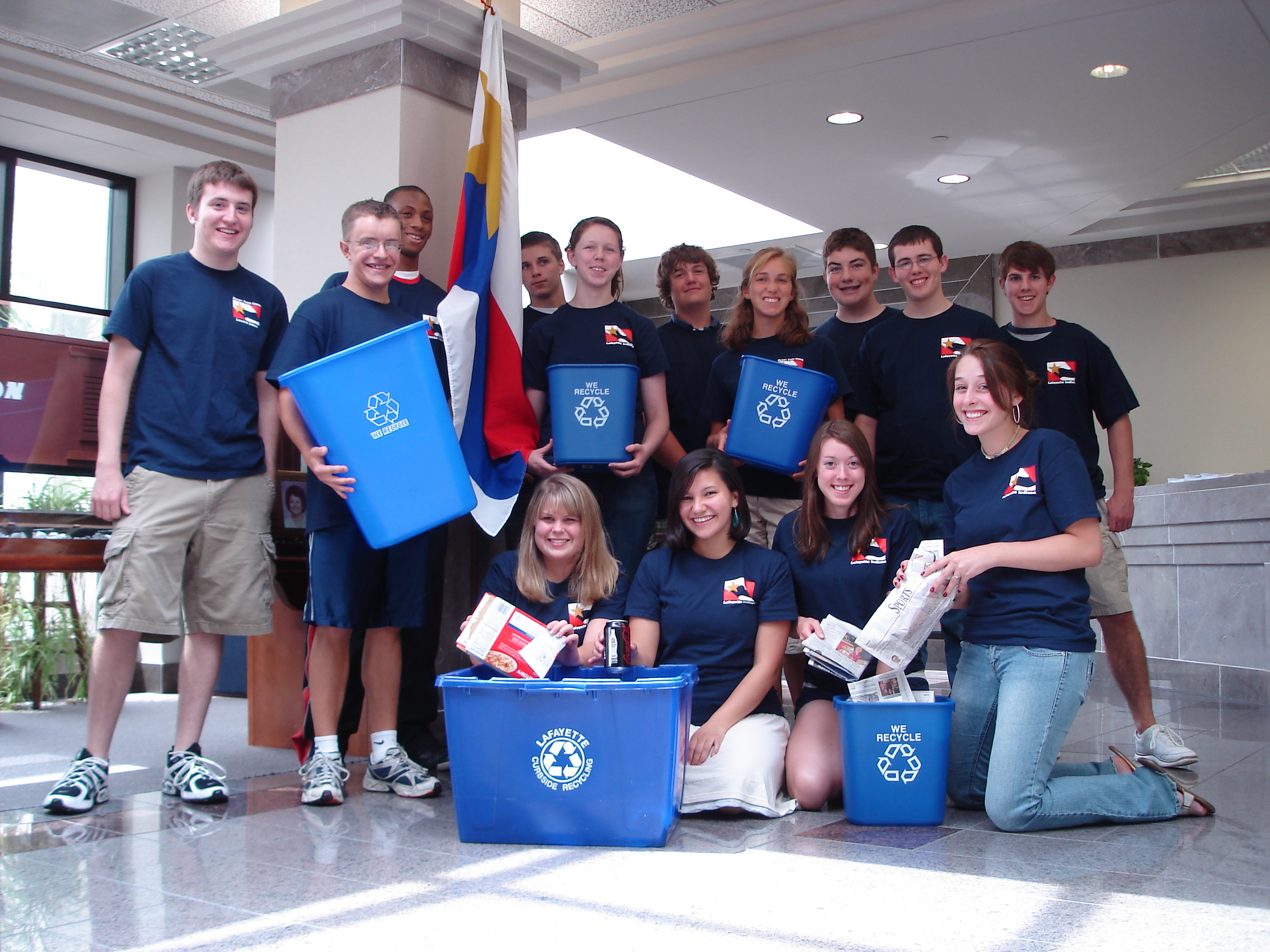A group of youths holding recycling bins
